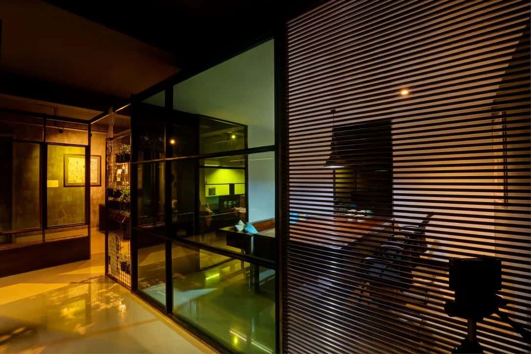 Glass-walled meeting room with wood slat partitioning inside a modern Kochi office at night