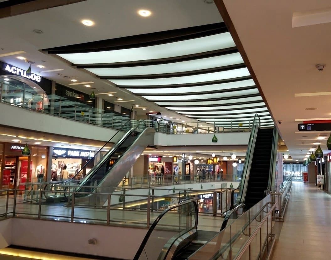Escalators, glazed atrium roof and storefronts inside a shopping mall